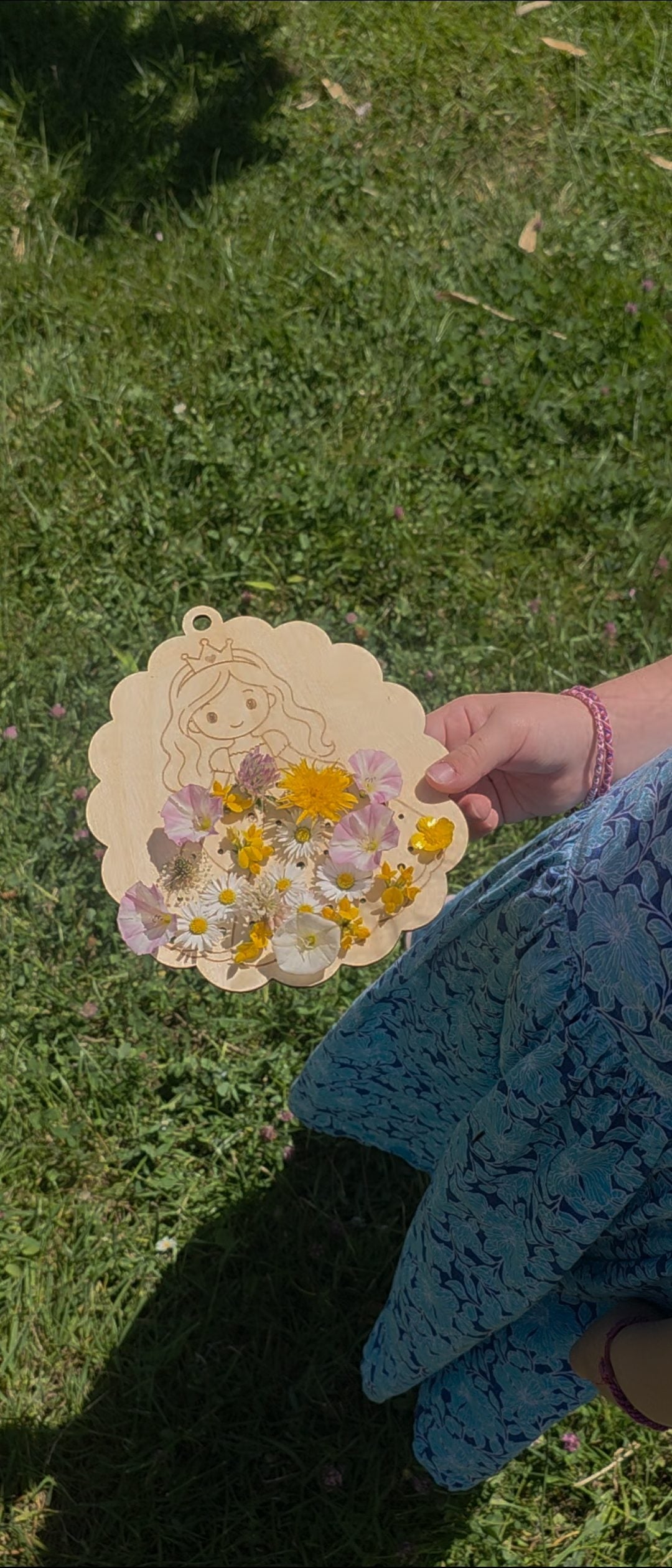 Le tableau Princesse rempli de fleurs, tenu dans l'herbe